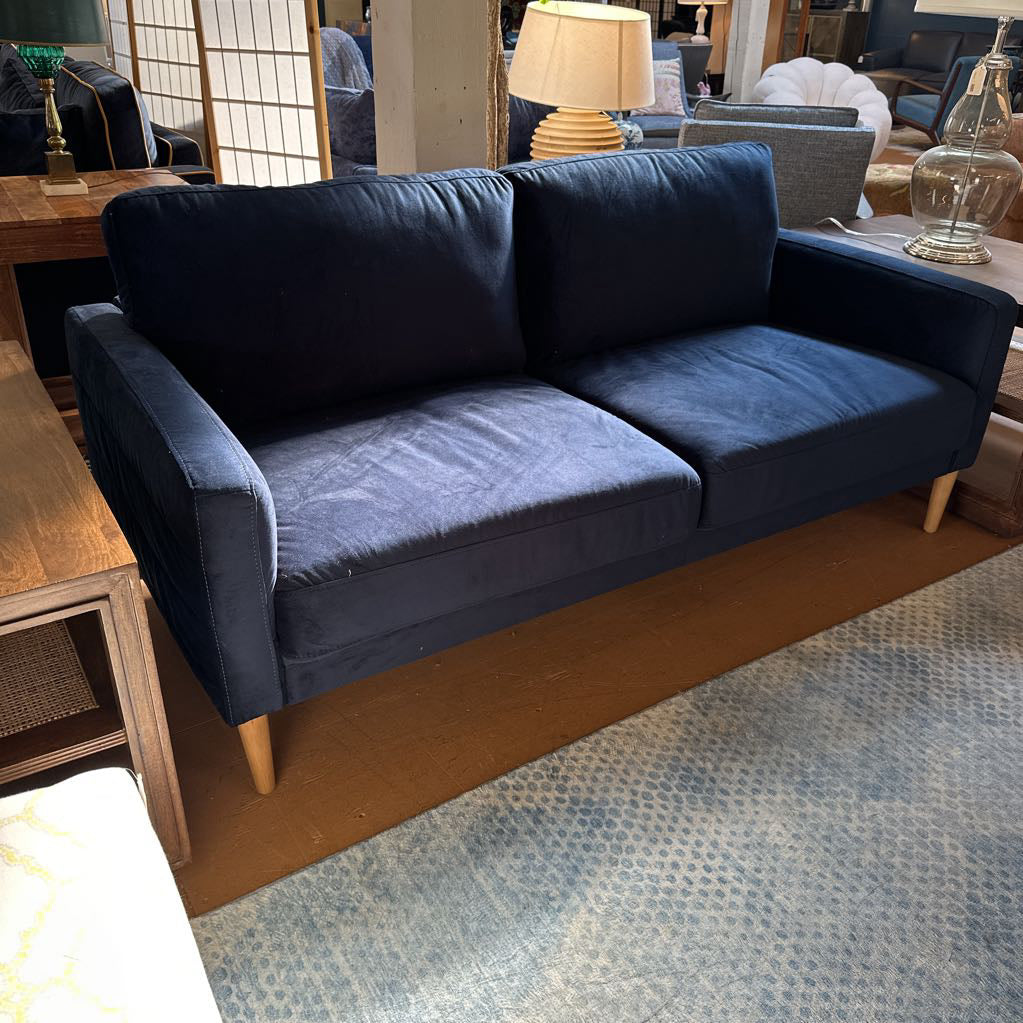 Blue sofa in a room with wooden flooring and furniture.