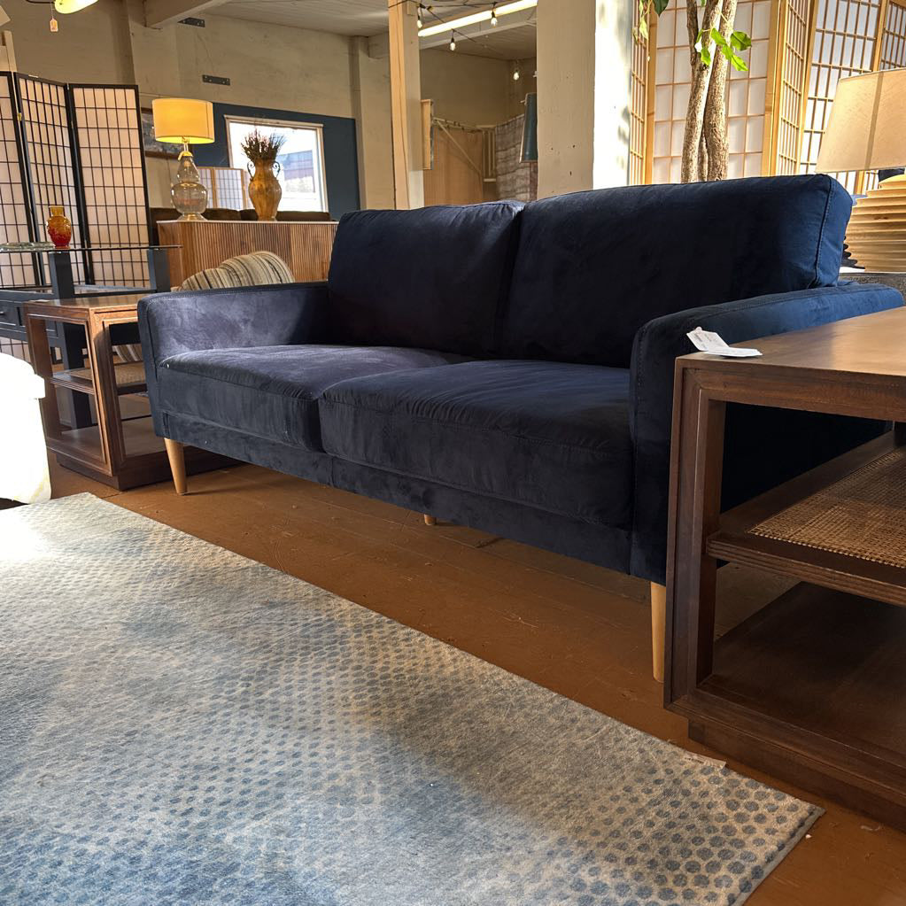 Blue sofa in a living room setting with wooden furniture and decor.