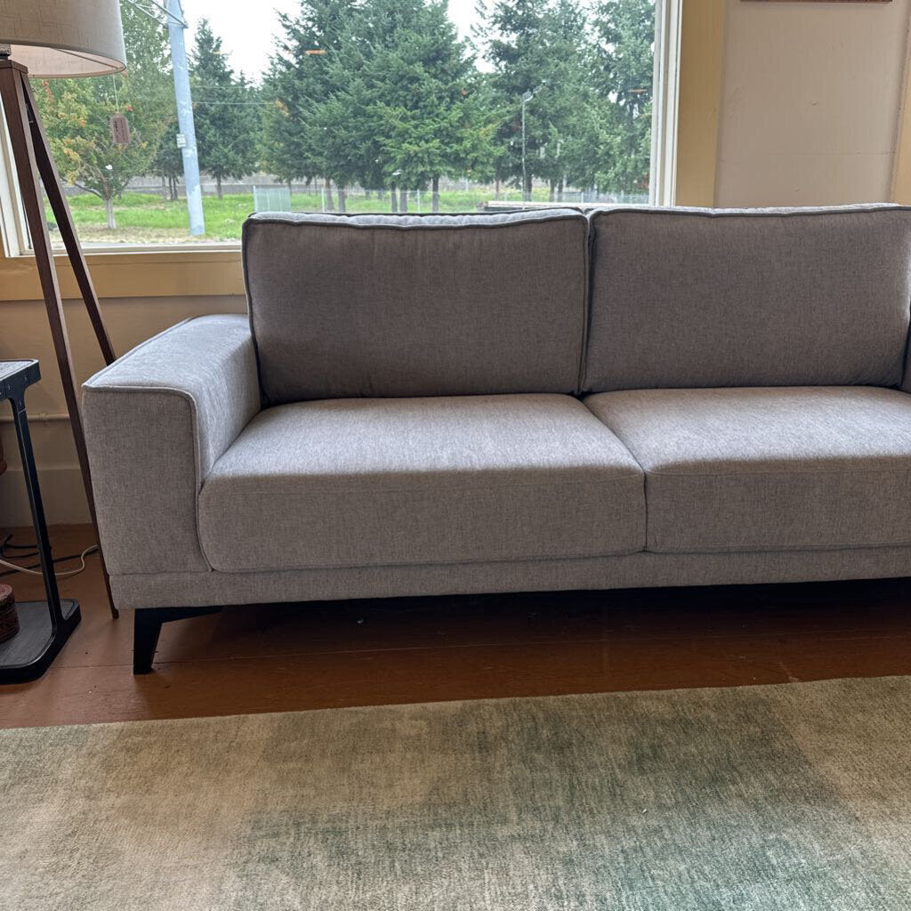 Gray sofa in a room with a window and lamp.