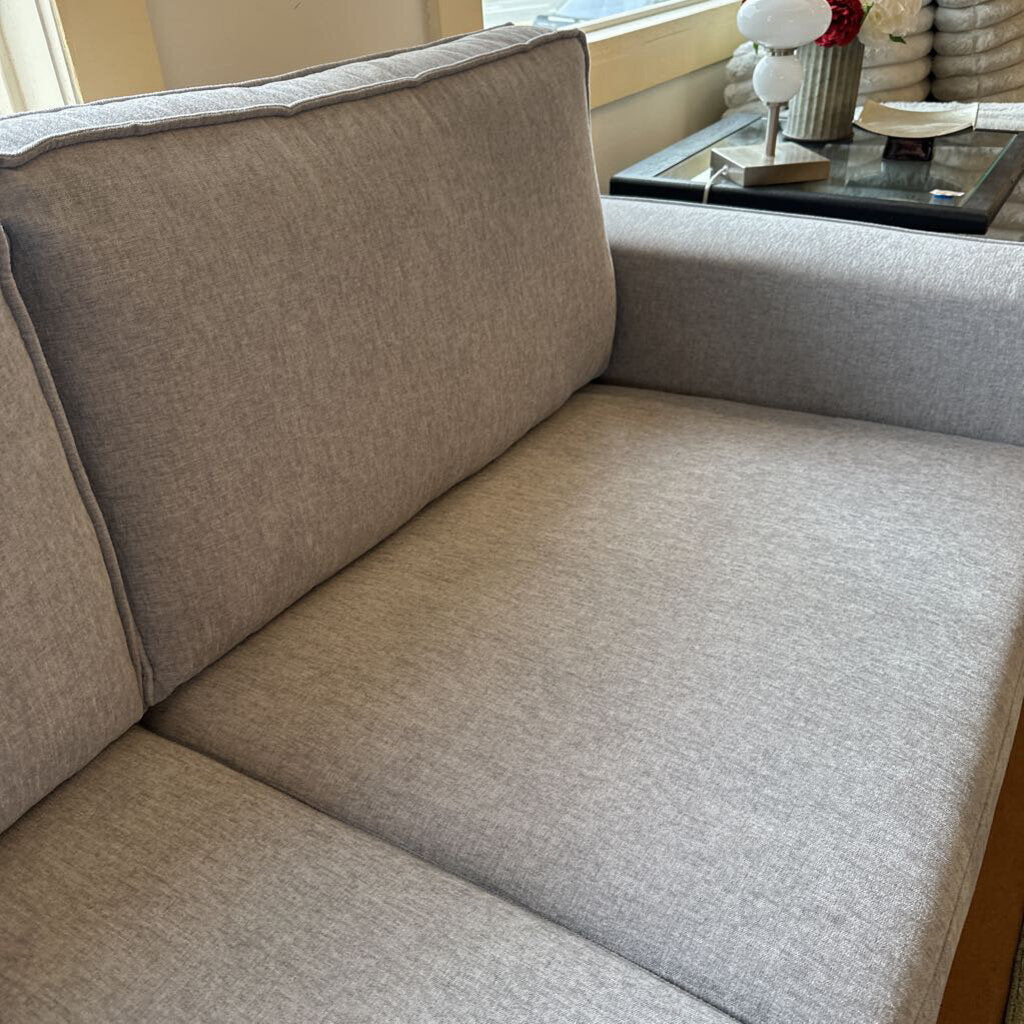 Gray sofa in a living room setting with a small table and decor items.