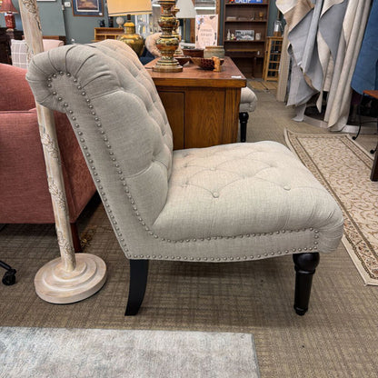 Light gray upholstered chair with nailhead trim in a furniture store setting