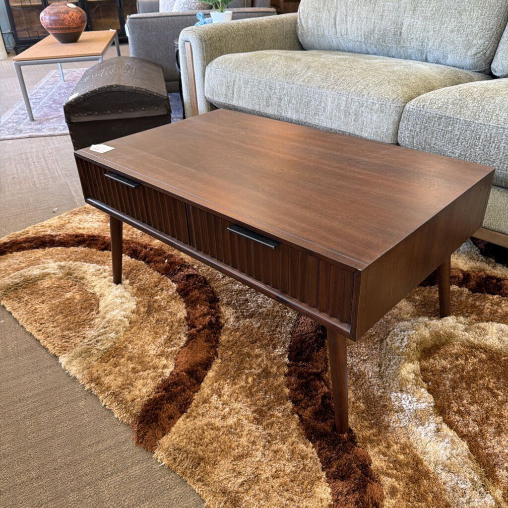 Wooden coffee table in a living room setting with a sofa and rug.