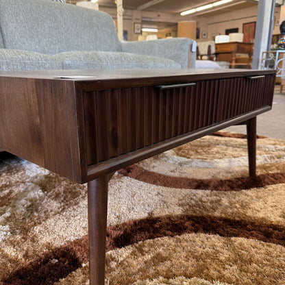 Wooden coffee table with a drawer in a furniture store setting