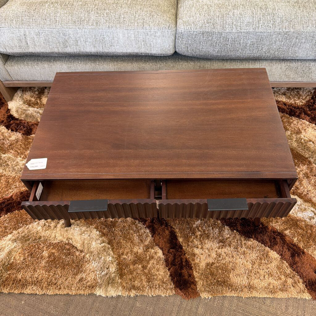 Wooden coffee table with lift-top design in front of a gray sofa on a patterned rug.