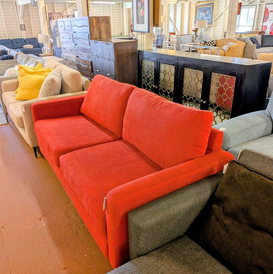Red sofa in a furniture store with various other sofas and decor items.
