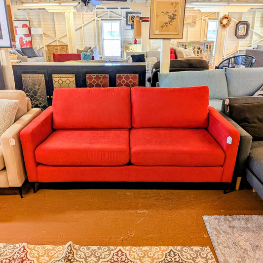 Red sofa in a furniture store with other sofas and decor items.