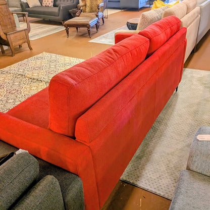 Red sofa in a living room setting with other furniture.
