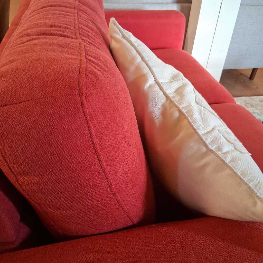 Close-up of a red sofa with a beige pillow