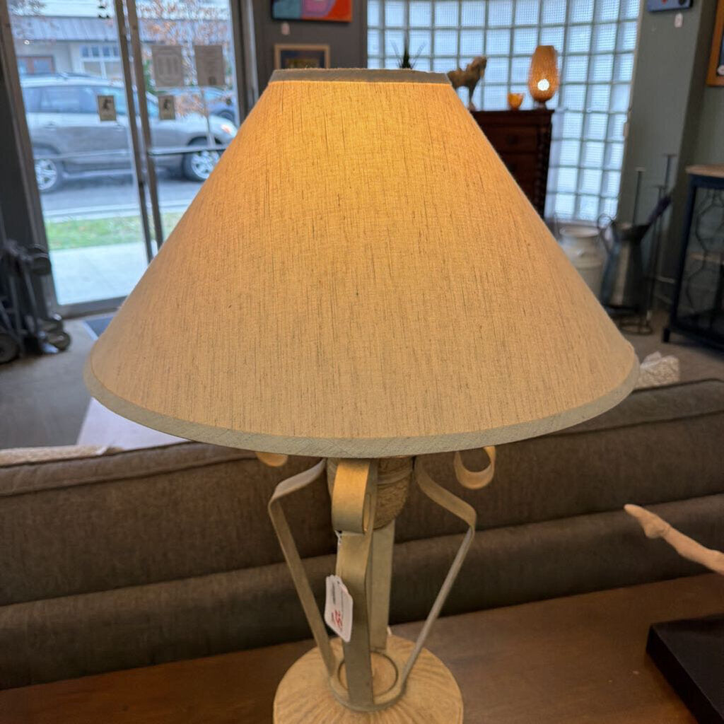 Table lamp with beige shade on a wooden surface in a room setting