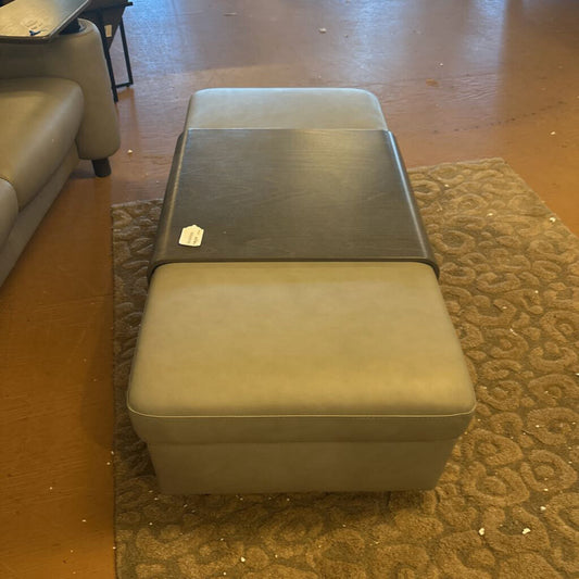 Brown leather ottoman on a patterned rug in a room with a couch.