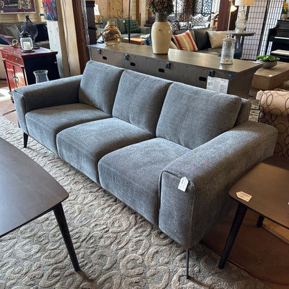 Gray sofa in a living room setting with furniture and decor.
