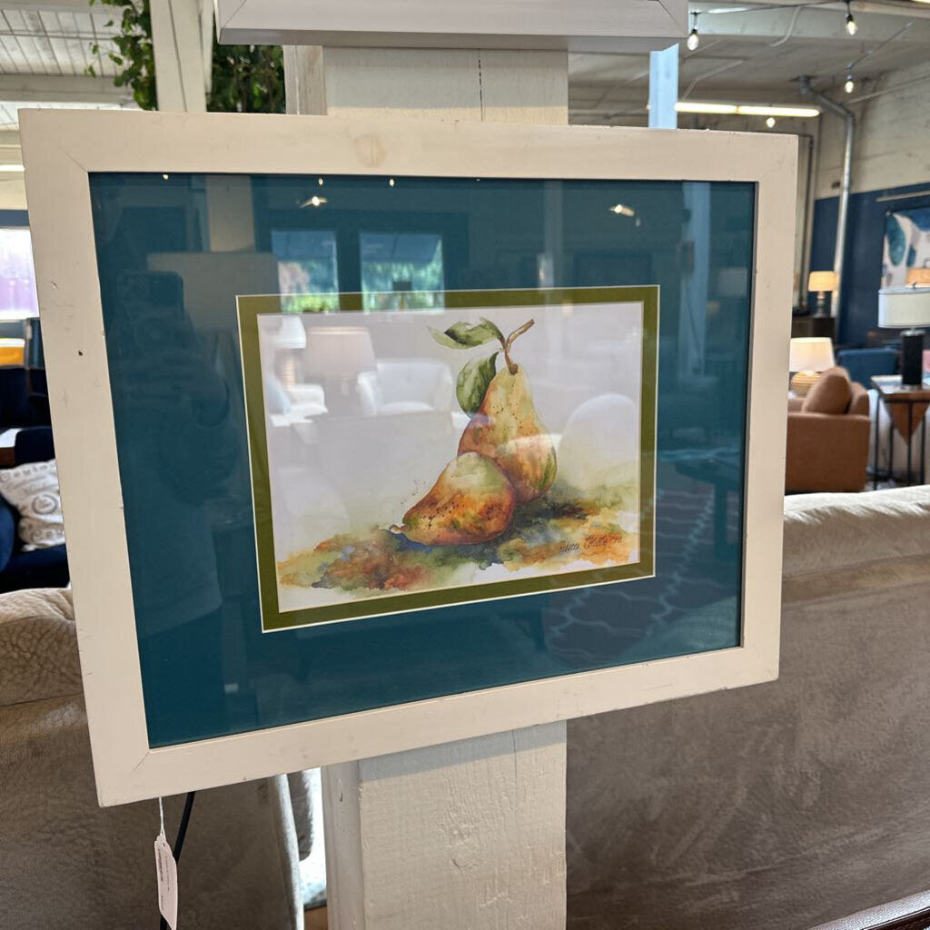 Framed artwork of pears on a stand in a store setting