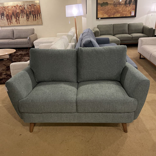 Gray sofa in a showroom setting with other furniture and decor.