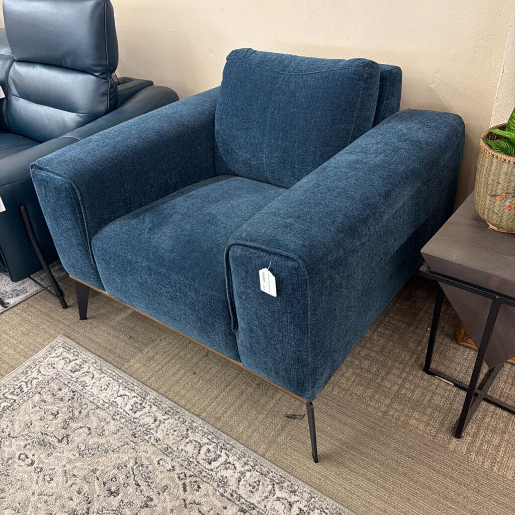 Blue armchair in a room with a rug and side table.