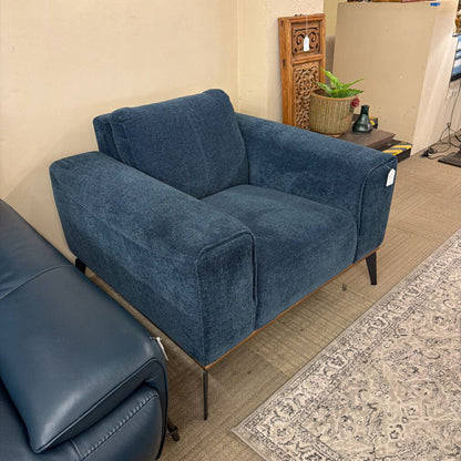 Blue sofa in a room with a patterned rug and wooden floor.