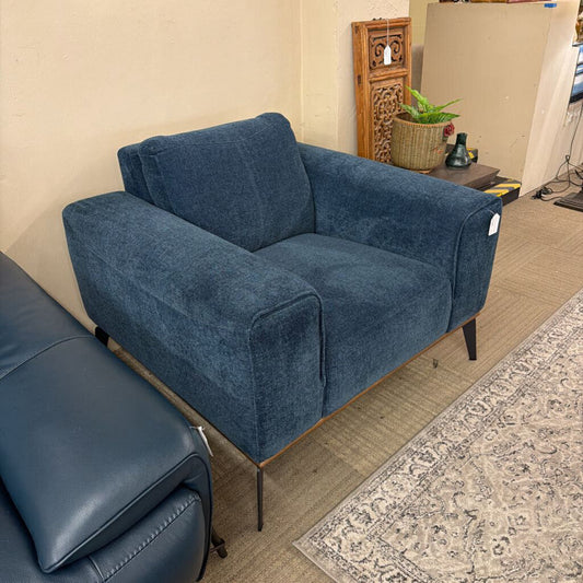 Blue sofa in a room with a patterned rug and wooden floor.