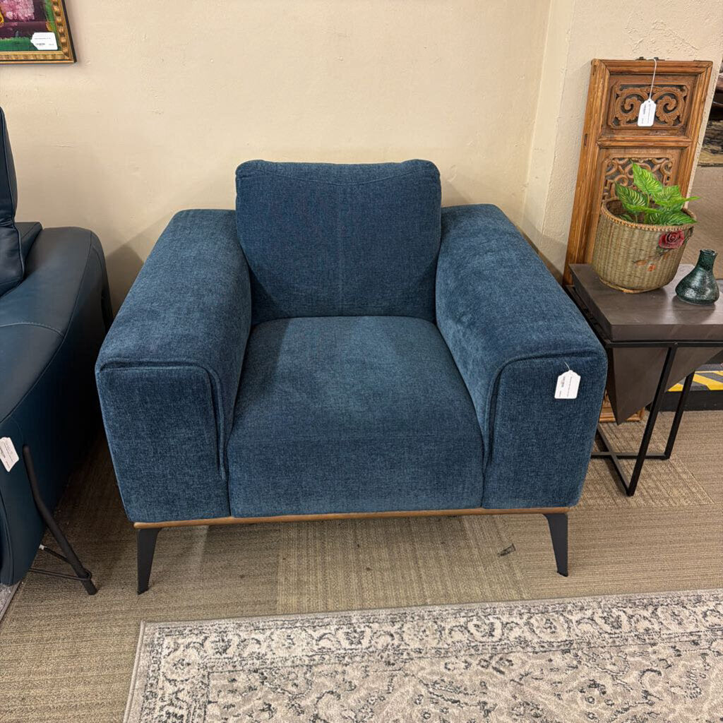 Blue armchair in a room with a beige wall and a small table with decor items.