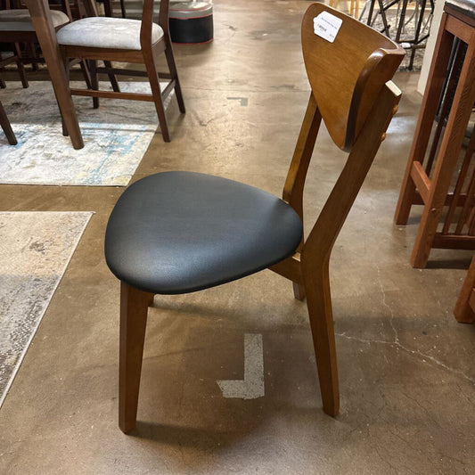 Wooden chair with a black seat on a tiled floor