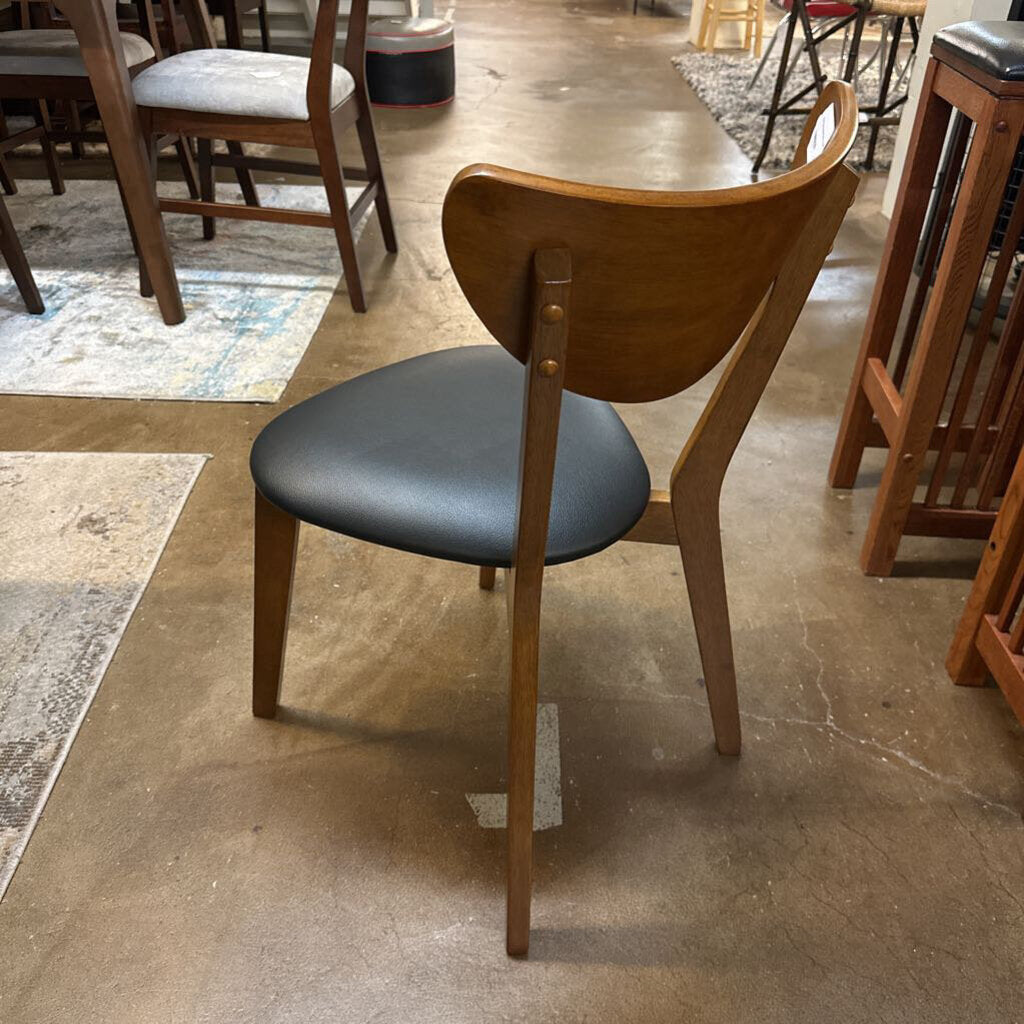 Dining chair with wooden frame and black cushioned seat in a room with tables and chairs.