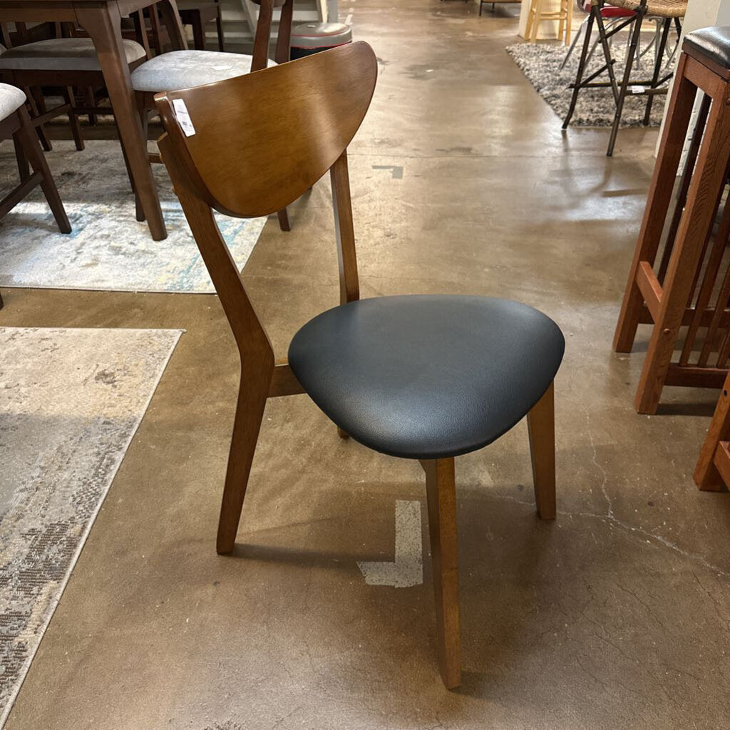 Wooden chair with a black seat in a room with other chairs and tables.