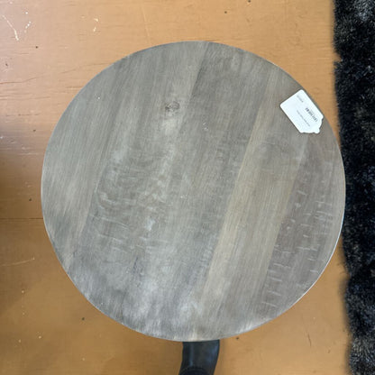 Round wooden cutting board with a visible brand label on a brown surface.