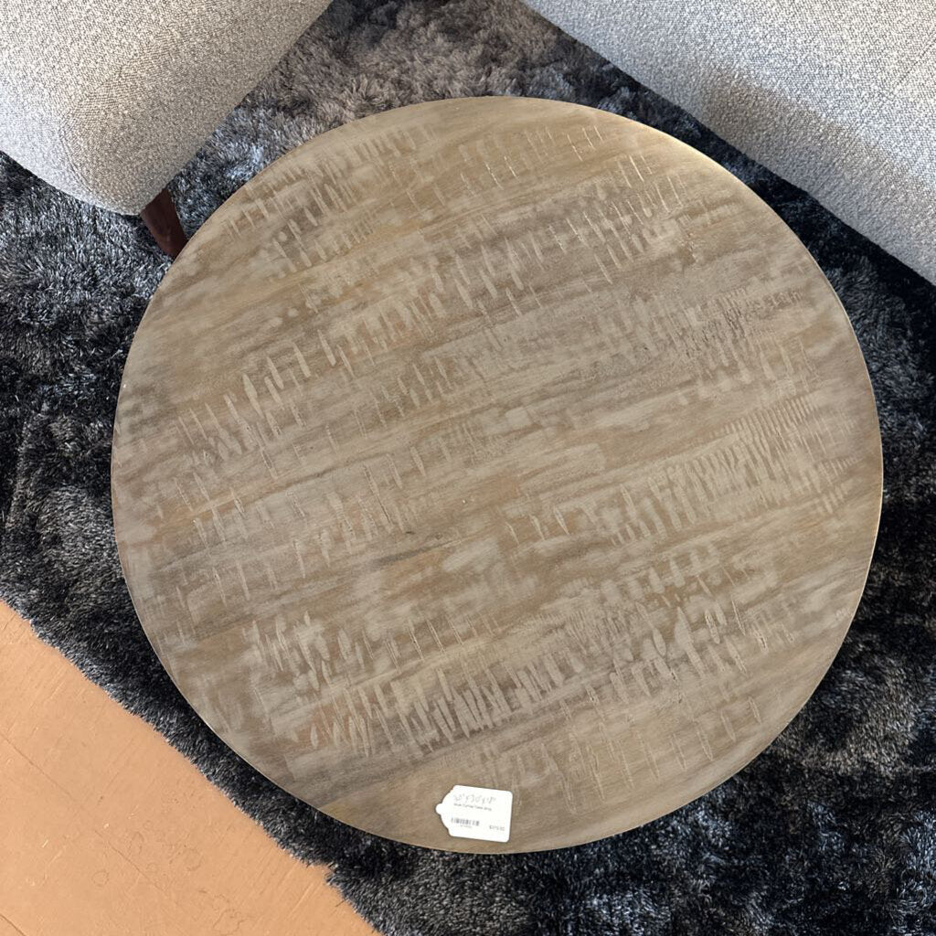 Round wooden stool with a textured surface on a dark gray surface.