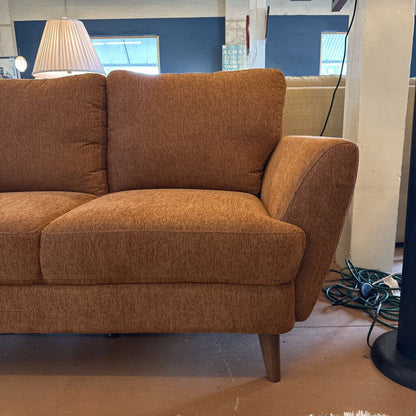 Brown sofa in a room with a lamp and wall art.