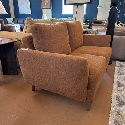 Brown upholstered chair in a room with other furniture and decor.