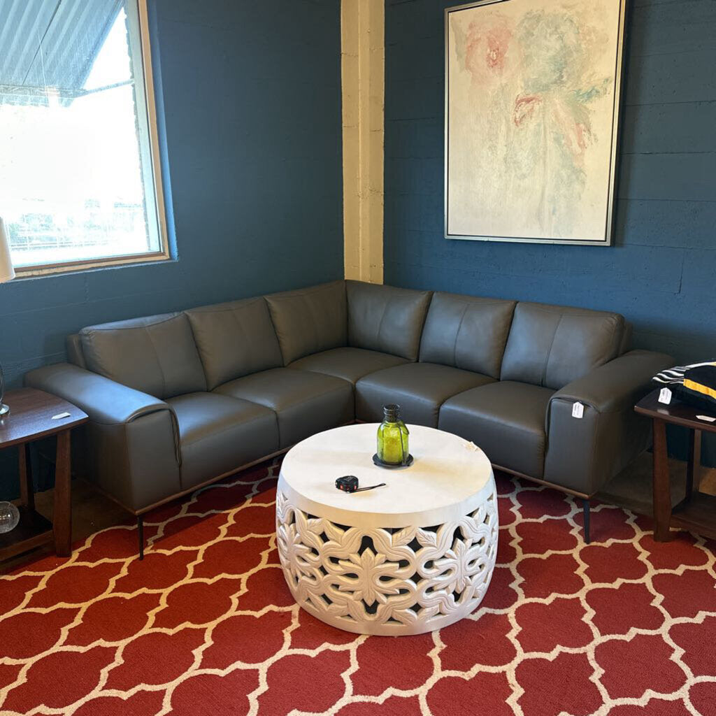Living room with a gray sectional sofa, white coffee table, and red patterned rug.