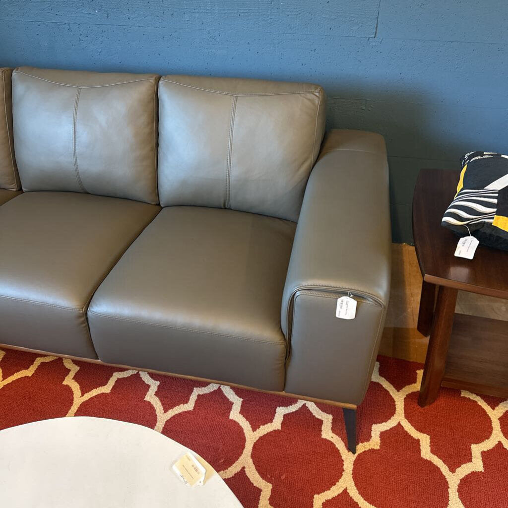 Gray sofa in a room with a red patterned rug and a wooden side table.