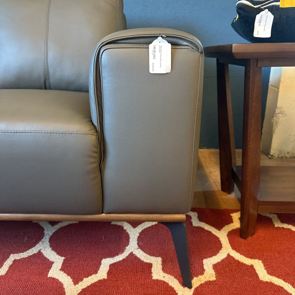 Gray suitcase with a tag on a red patterned rug next to a gray couch and wooden table.