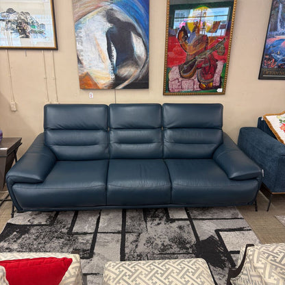 Blue leather sofa in a room with colorful abstract paintings on the wall.
