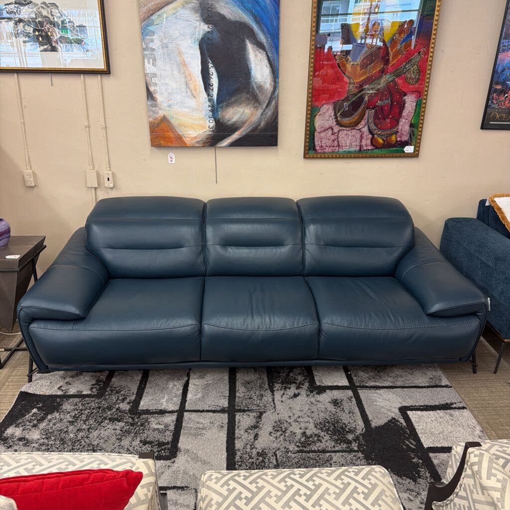Blue leather sofa in a room with abstract art on the walls.