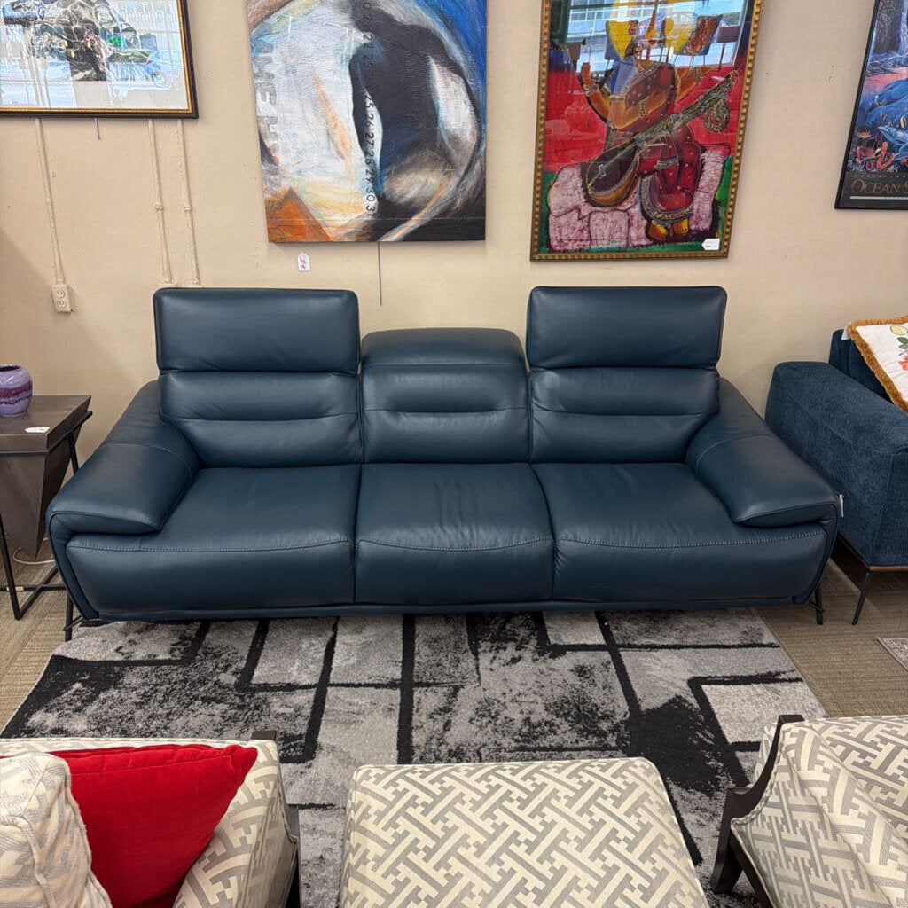 Blue leather sofa in a room with abstract art on the walls.