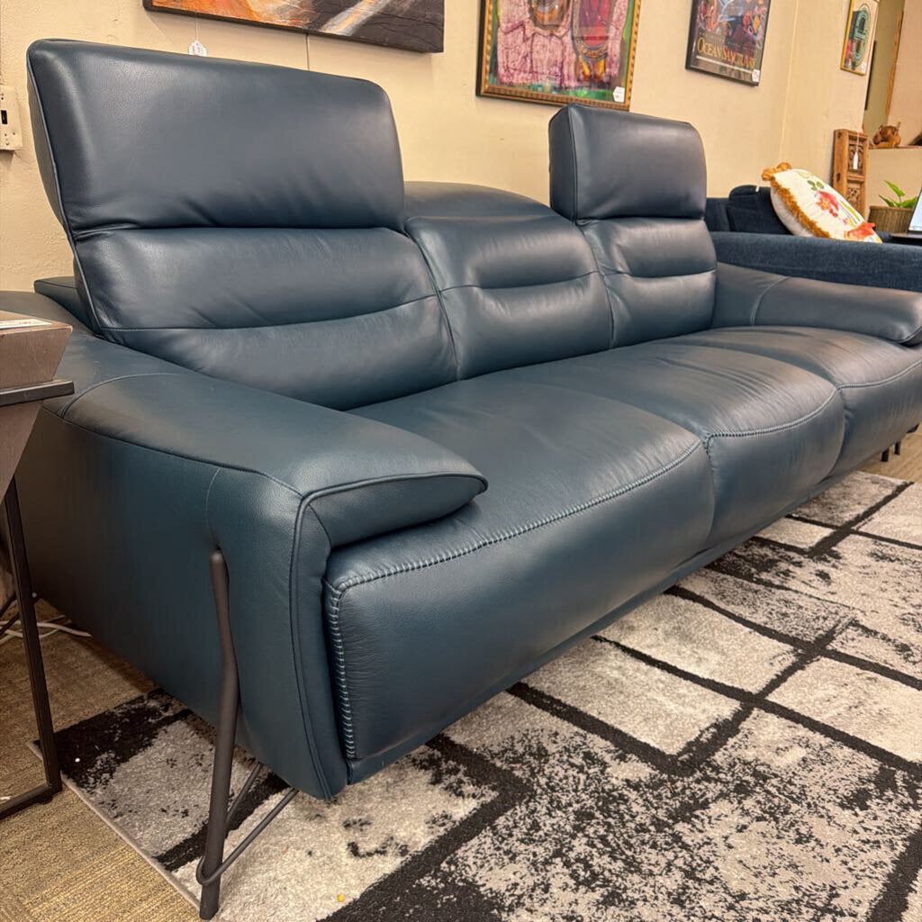 Blue leather sectional sofa in a living room setting with a rug and wall art.