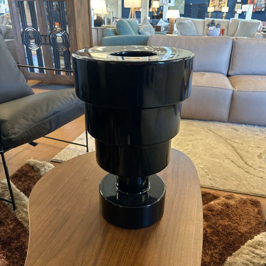Black cylindrical object on a wooden table in a living room setting