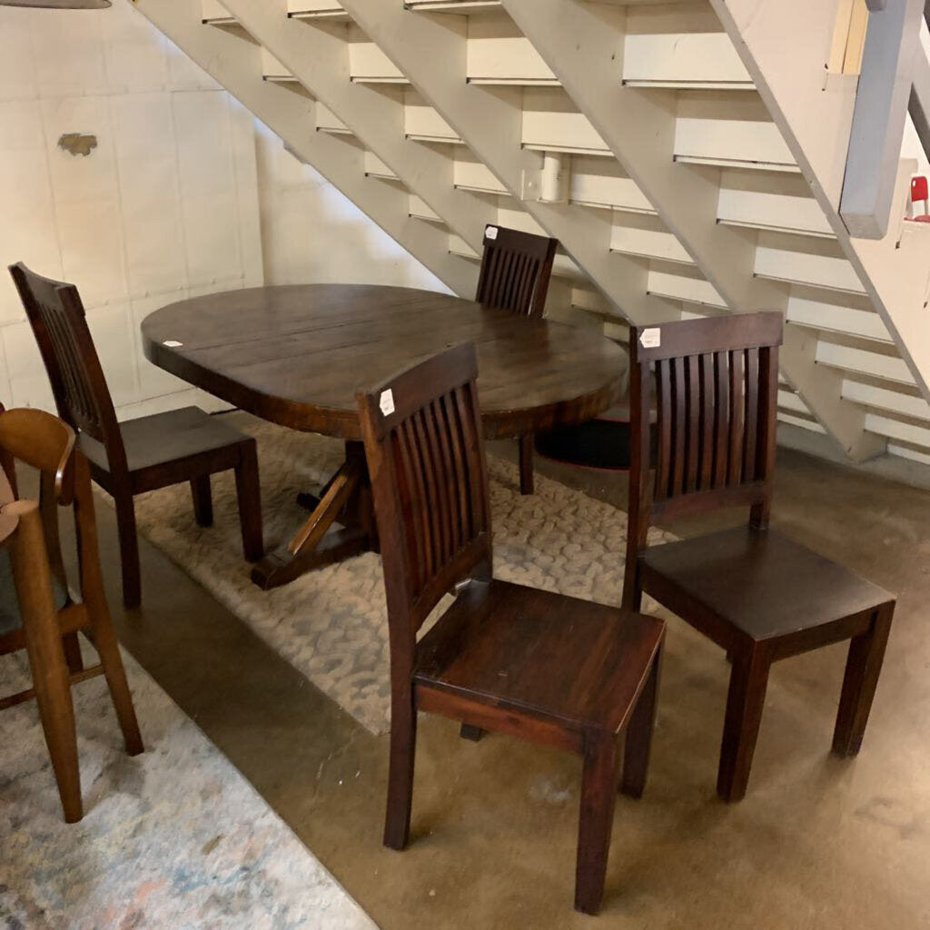 Wooden dining table with chairs under a staircase