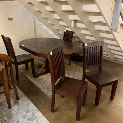 Wooden dining table with chairs under a staircase