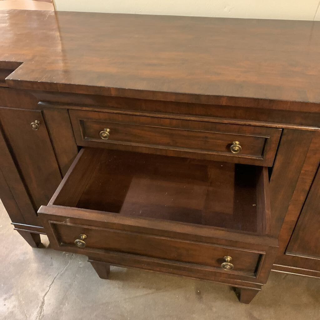 Wooden dresser with an open drawer on a concrete floor