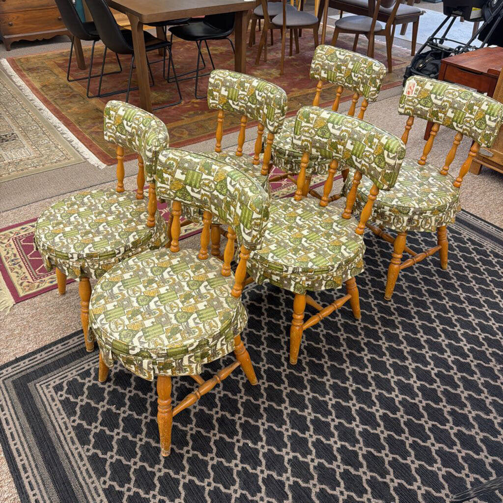 Set of wooden chairs with green patterned cushions on a patterned rug.