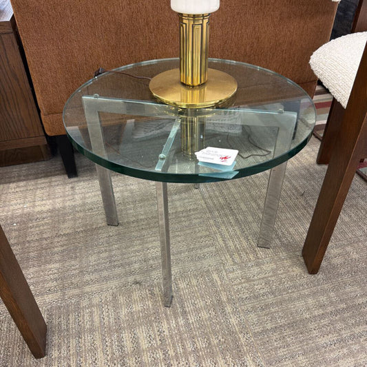 Glass side table with a gold lamp on a carpeted floor