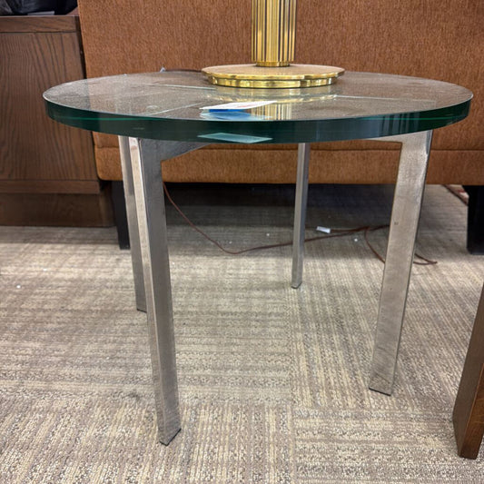 Round glass table with metal legs on a carpeted floor