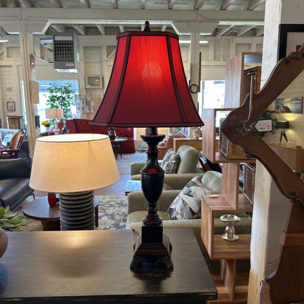 Red lampshade on a table in a living room setting