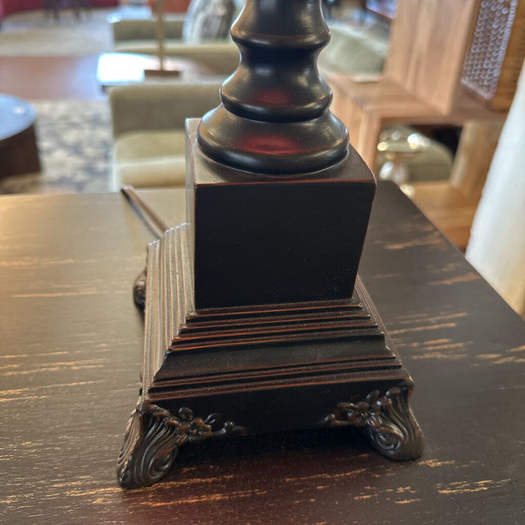Decorative black pedestal on a wooden surface with blurred background