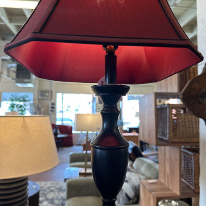 Close-up of a red lampshade with a blurred indoor setting in the background