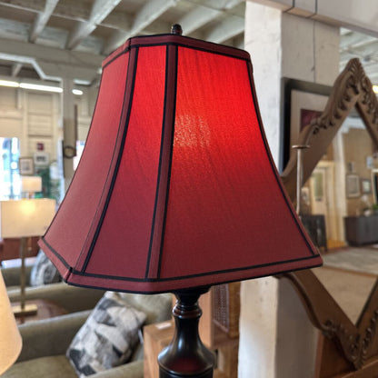 Red lampshade on a stand with a blurred indoor background