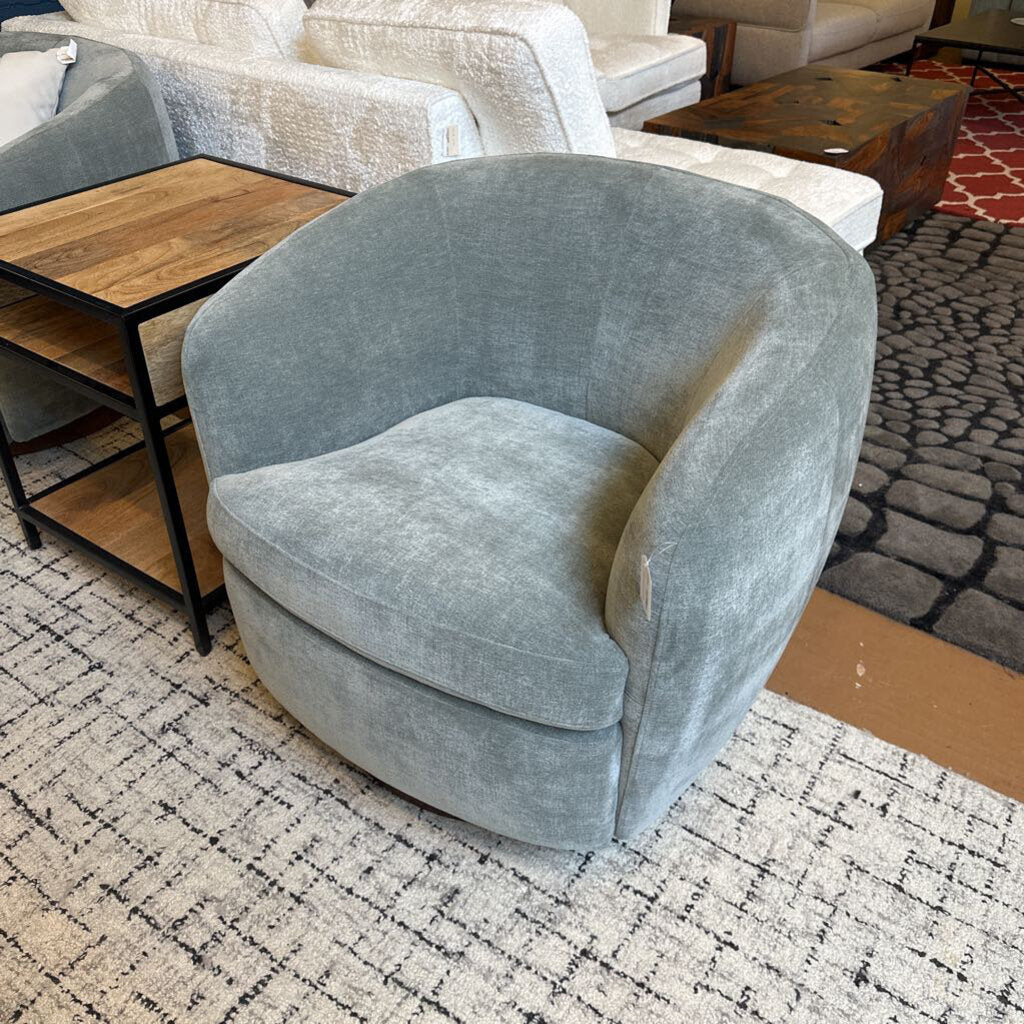 Gray velvet armchair in a living room setting with a rug and furniture.