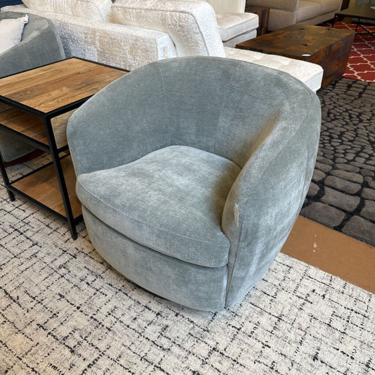 Gray velvet armchair in a living room setting with a rug and furniture.