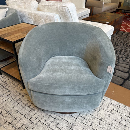 Gray swivel chair in a room with furniture and a rug.