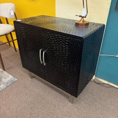 Black textured cabinet with a lamp on top in a room with yellow and blue walls.